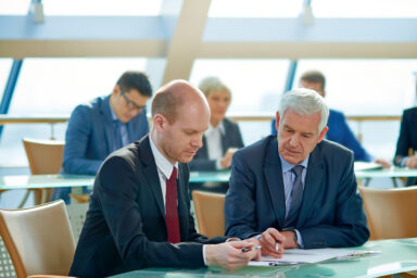 Zwei Männer schauen auf ein Dokument und unterhalten sich.
