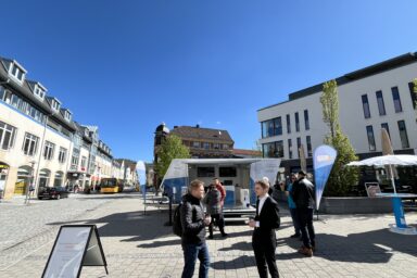 Menschen unterhalten sich auf dem Marktplatz. Im Hitergrund das Gigabit-Mobil.