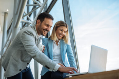 Mann und Frau schauen von oben auf einen Laptopbildschirm.