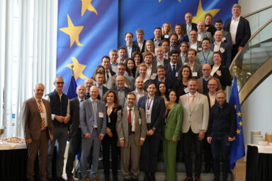 Teilnehmende der BCO-Konferenzen. Im Hintergrund ist eine Europaflagge zu sehen.