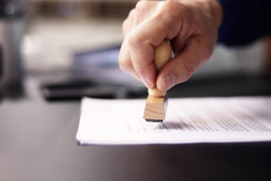 Auf dem Foto setzt jemand ein Stempel auf ein Dokument.